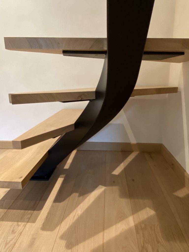 Détail des marches en bois massif sur structure acier noire, design contemporain